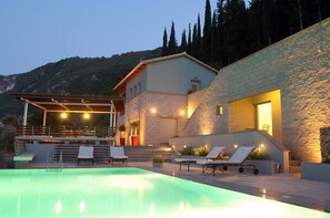 Et moderne hus med swimmingpool, udendørs møbler og en stenvæg.