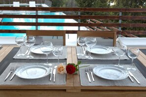 A dining table set for two with a pool view, two chairs, and a rose centerpiece. - Villa Santolina - Three Bedroom Villa, Sleeps 6 (Lefkada City)