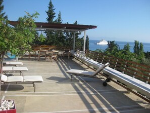 Une terrasse sur le toit, dotée de chaises longues, d’un espace repas et offrant une vue sur la mer.