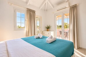 Ein Hotelzimmer mit Bett, Schminktisch, Zimmerpflanze und Blick ins Freie.