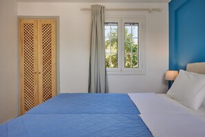 Ein Schlafzimmer mit einem Bett, einem Vorhangfenster, einem Nachttisch mit Lampe und einem Holzschrank mit Gittermuster.