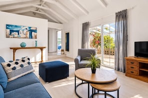 A modern living room with a sofa, ottoman, armchair, and a coffee table. - Villa Thalia Galini - Two Bedroom Villa, Sleeps 4 (Vassilikos)