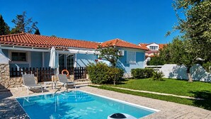 Il s’agit d’une propriété résidentielle dotée d’une piscine, d’une cour arrière clôturée et d’une maison dont le toit est recouvert de tuiles rouges.