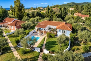 A residential property with a swimming pool, surrounded by lush greenery and a view of the sea. - Villa Thalia Galini - Two Bedroom Villa, Sleeps 4 (Vassilikos)