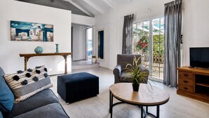 Un salon comprenant un canapé, un pouf, une table ronde et un téléviseur.