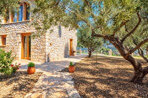A stone building with a stone pathway leading to the entrance, surrounded by olive trees and potted plants. - Villa Tireda Tria - Three Bedroom Villa, Sleeps 6 (Koridallos)