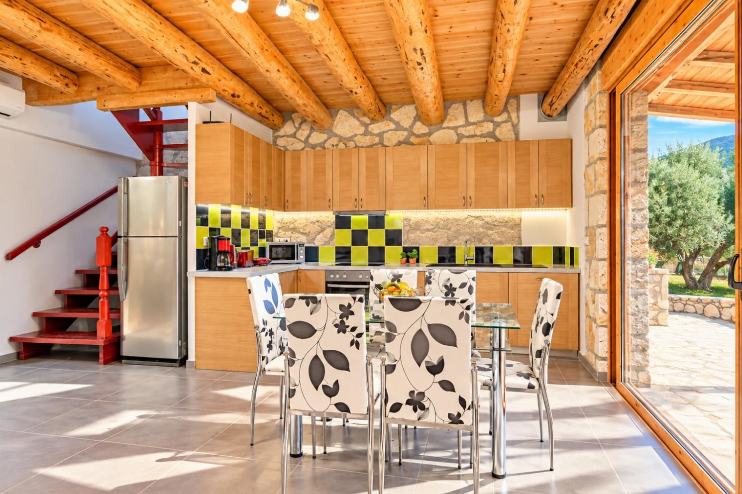 Rustic kitchen and dining area with wooden cabinetry, colourful tiled backsplash, and exposed ceiling beams.