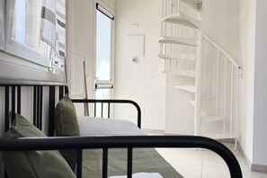 A bedroom with a bed, a window, a white door, and a white spiral staircase. - [Casa di Sara]Loft-6 lits-Air conditioning (La Spezia)