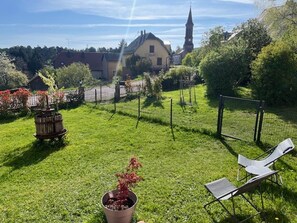 A grassy backyard with a lawn chair, a potted plant, and a fence. - Les Brimbelles 4* with an enclosed garden / spa access (Aubure)