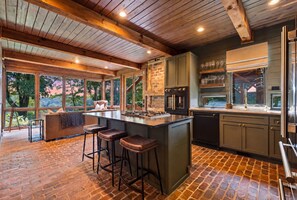 A modern kitchen with a large island, bar stools, and a view of the outdoors. - Highlands Mountain Meadow -Luxury 4/3.5 cabin-Mins to Highlands-Views- Hot Tub (Scaly Mountain)