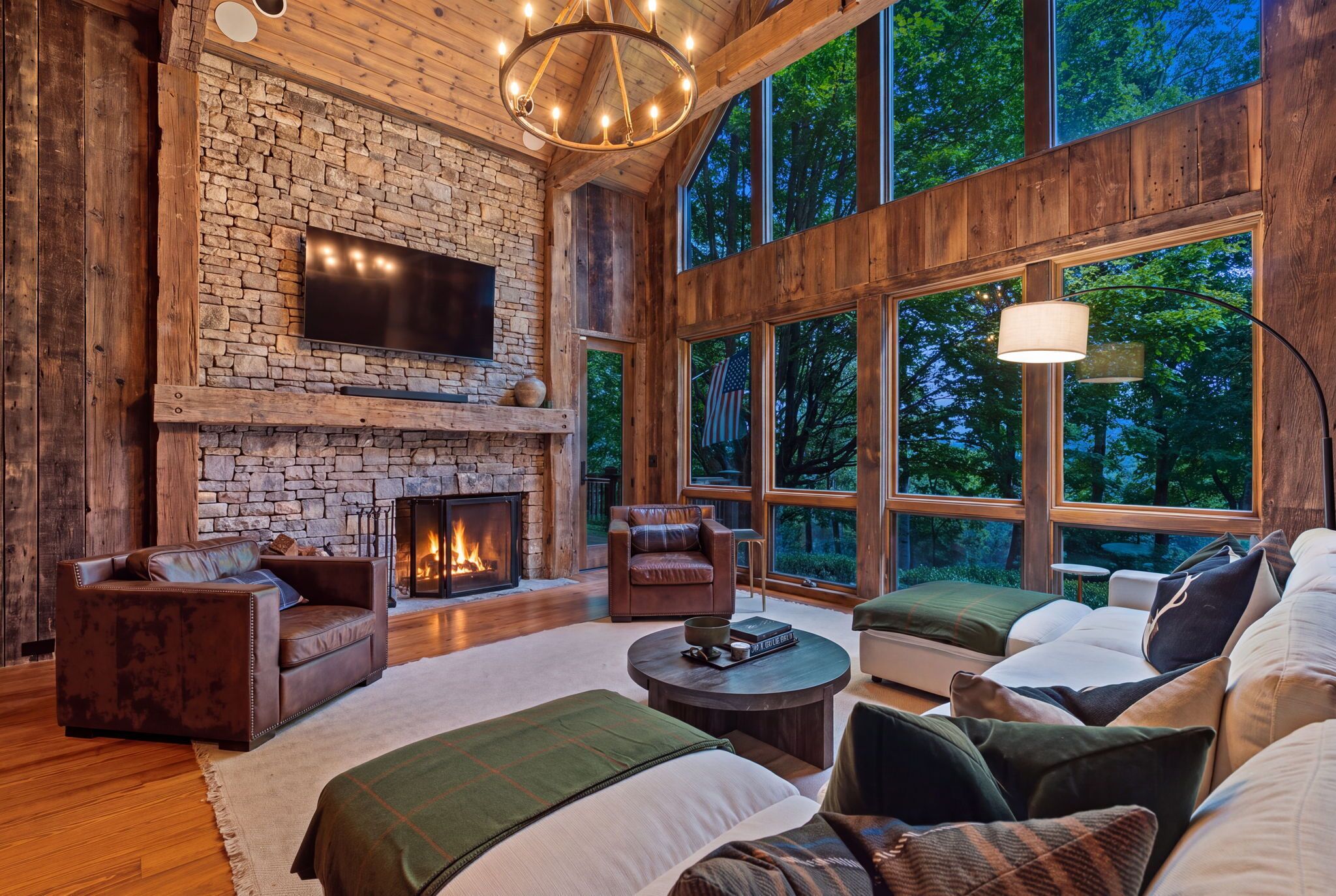 Ein gemütliches Interieur mit Kamin aus Stein, Ledersofas und großen Fenstern mit Blick ins Freie.