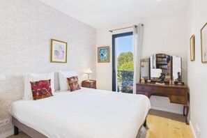 A hotel room with a bed, a desk with a mirror, and a view of the outdoors. - -L'Atelier- 2-Bedroom Apartment with Balcony in the Heart of Downtown (Concarneau)