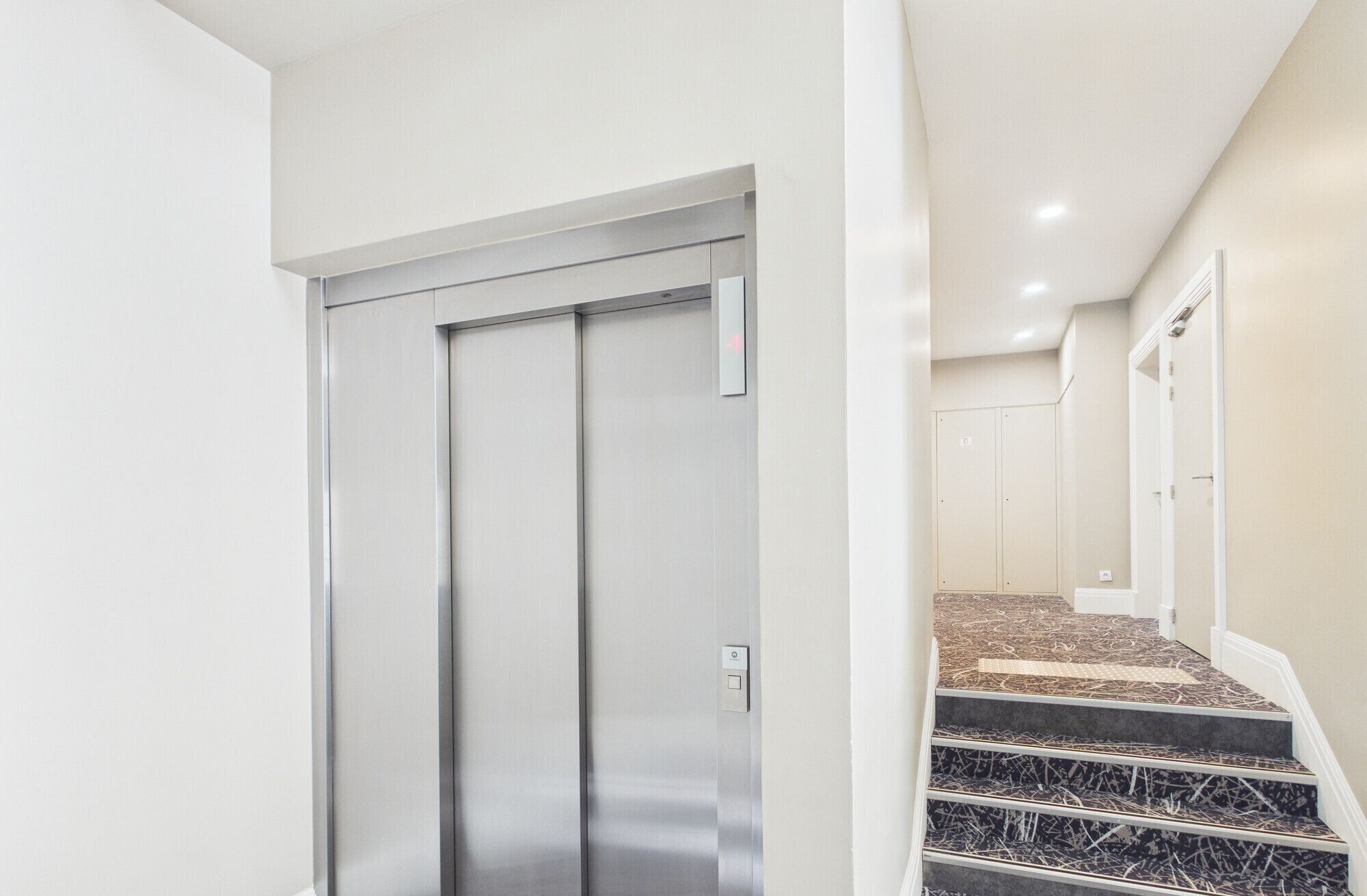 Een moderne lift met een metalen afwerking en een bedieningspaneel.