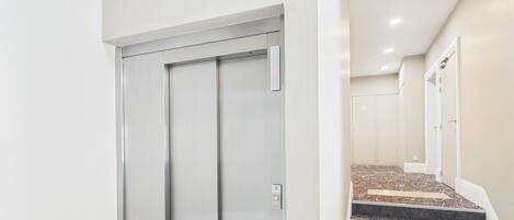 Een moderne lift met een metalen afwerking en een bedieningspaneel.