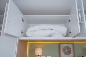 A neatly made bed in a white room with a wooden headboard and a bedside table with a lamp. - Corporate Stays First Living - 805 (Asunción)