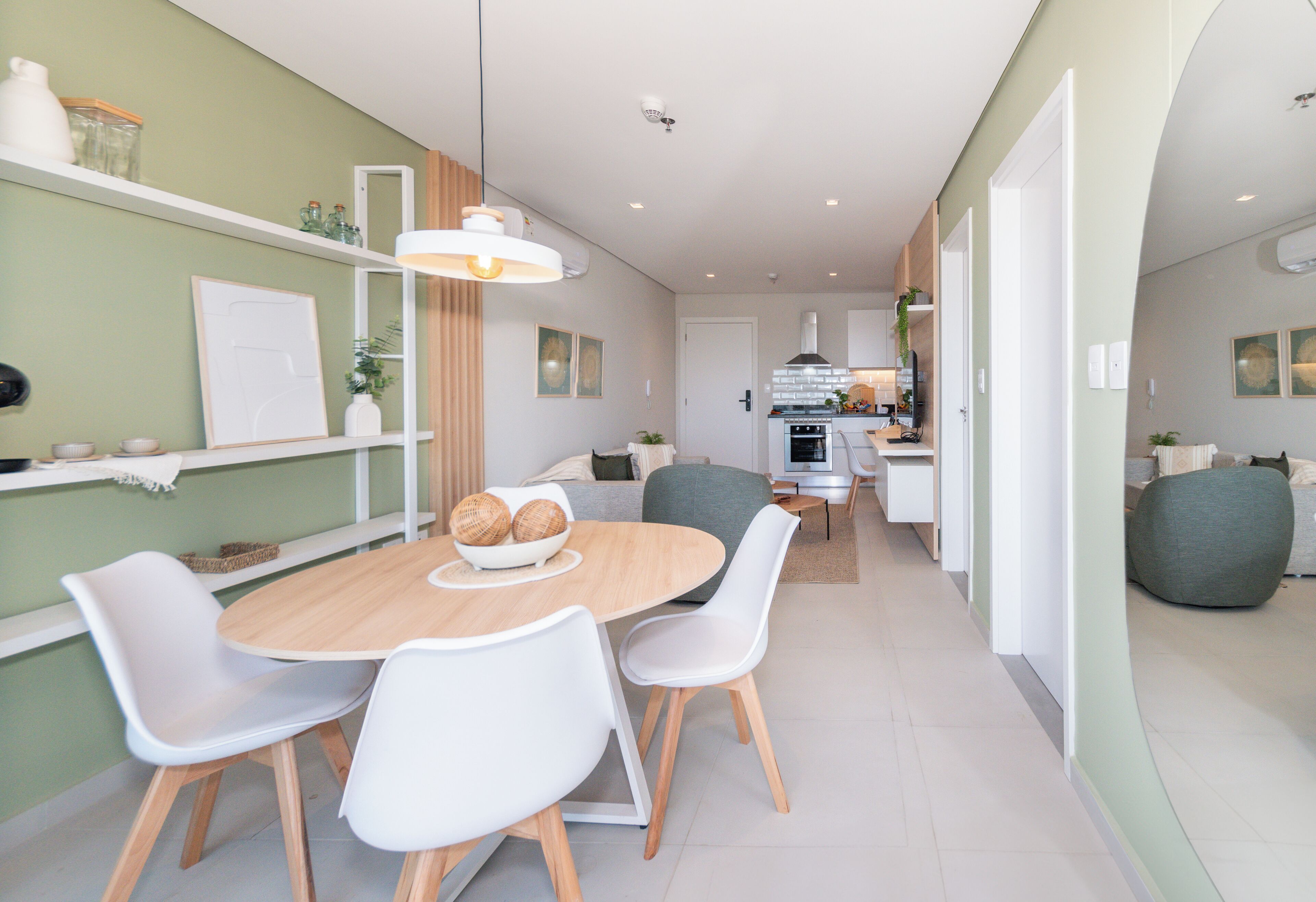 Una cocina moderna con armarios blancos, una isla central y un comedor con una mesa redonda y sillas.