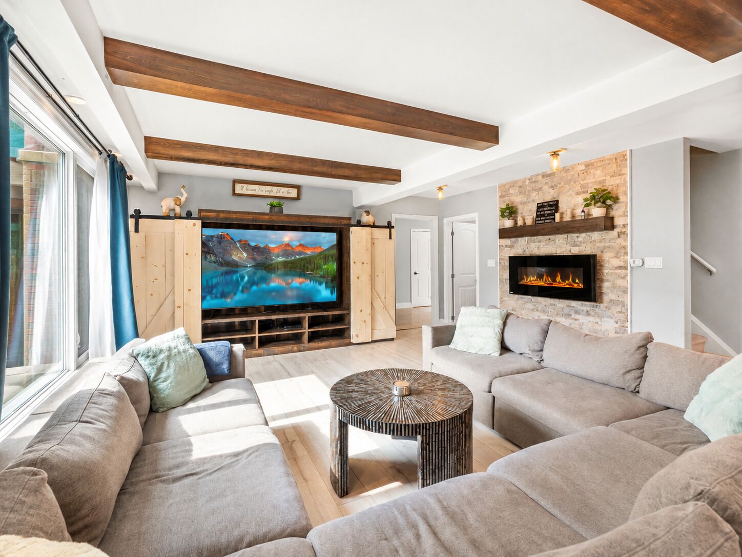 A modern living room with a large flat-screen TV, a fireplace, and a cozy seating area.
