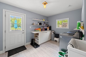 Ett kompakt kök med vita skåp, en inbyggd diskmaskin och ett fönster med utsikt över grönområden.