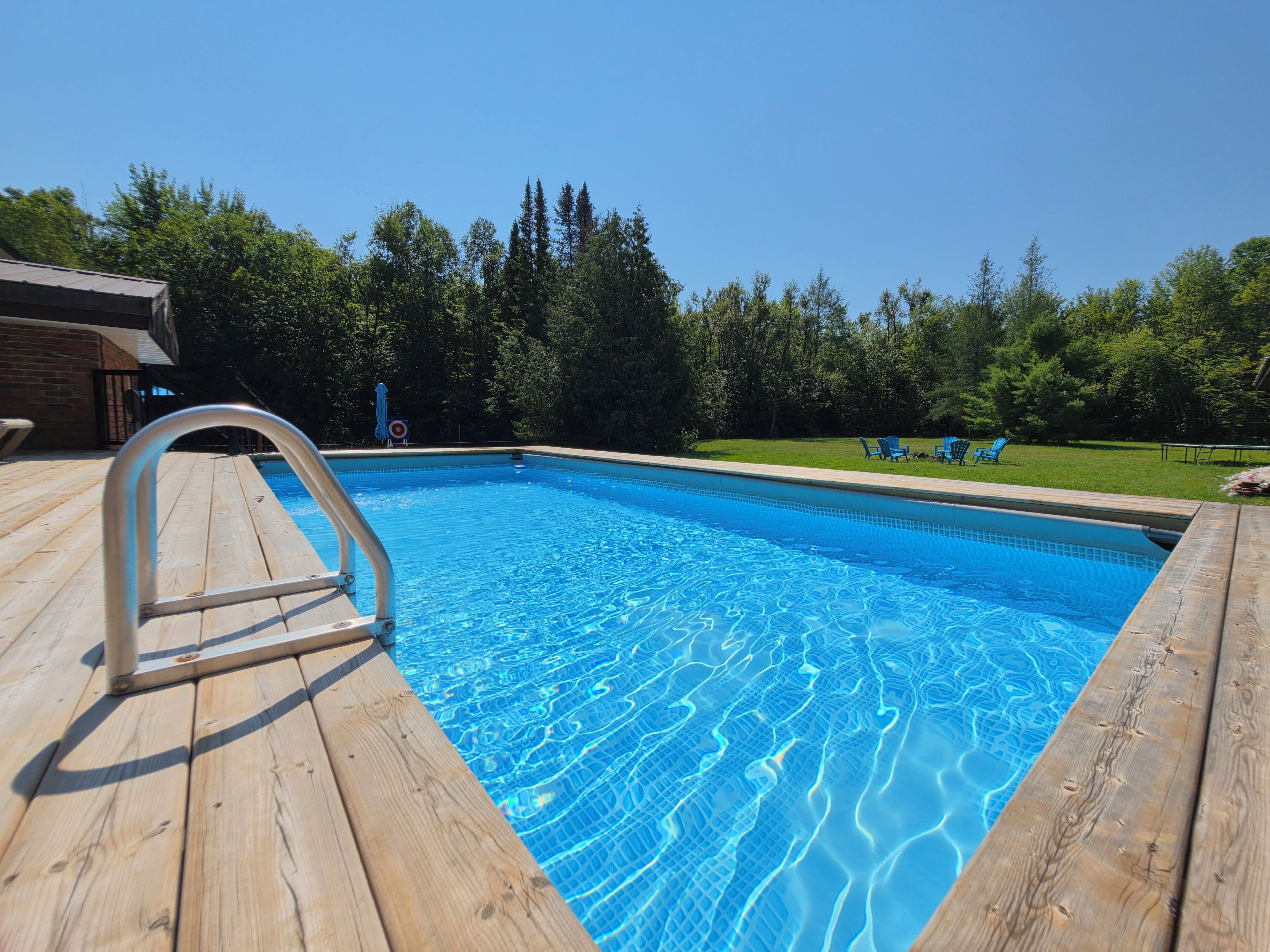 Una piscina rectangular con cubierta de madera y una escalera metálica.