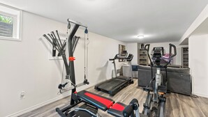 A home gym with a treadmill, a stationary bike, and a cable machine.