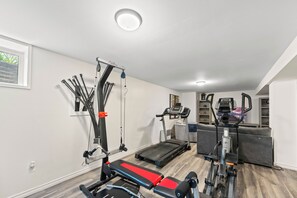 A home gym with a treadmill, a stationary bike, and a cable machine.
