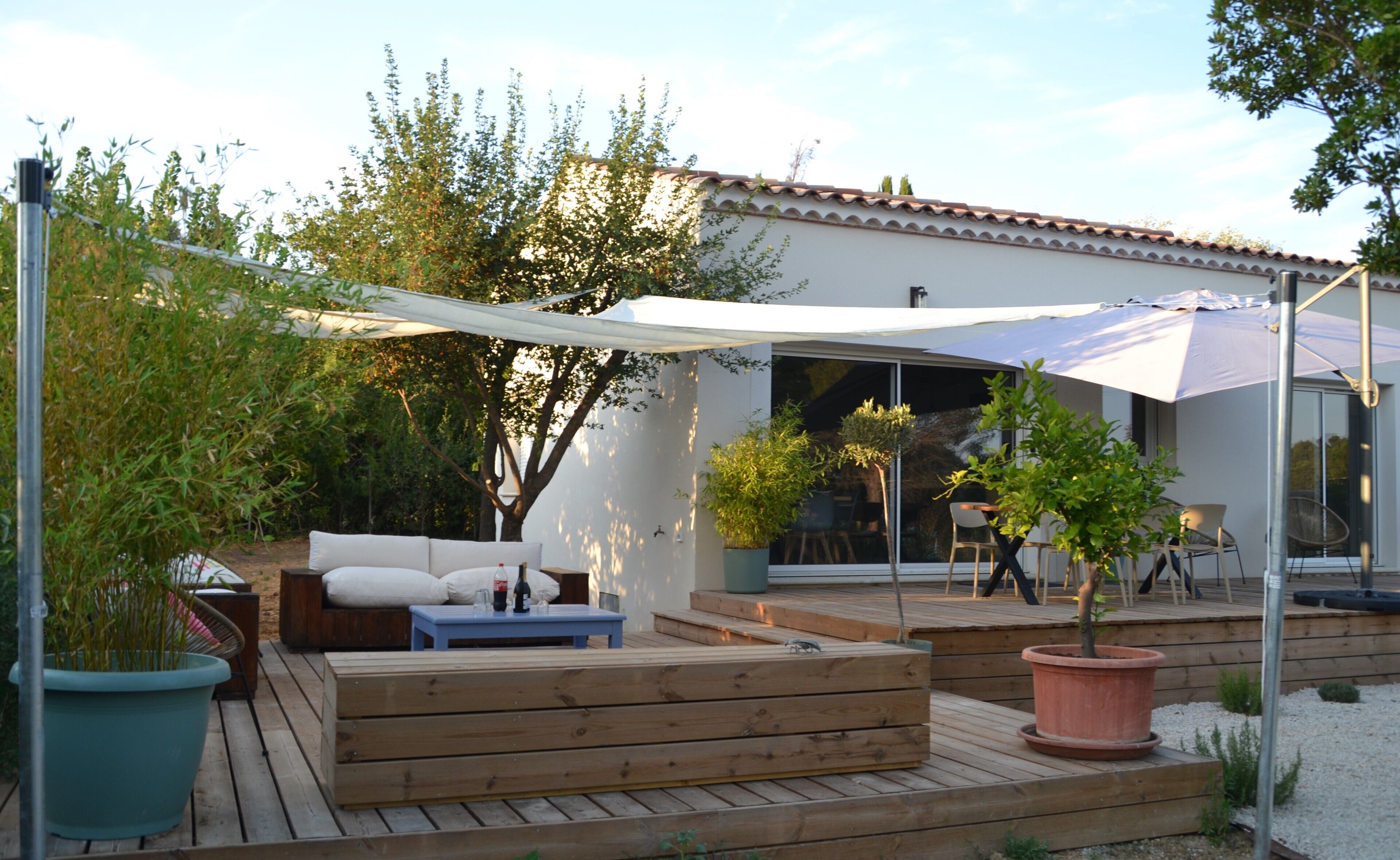 Une terrasse en bois avec des meubles d’extérieur, une pergola et des plantes en pot.