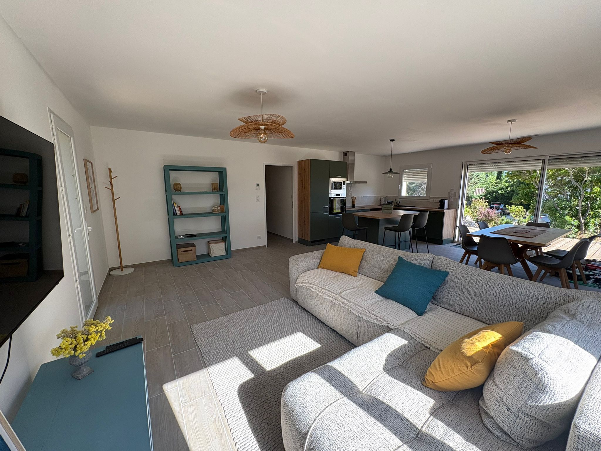 A modern living room with a sofa, a dining area, and a kitchen.