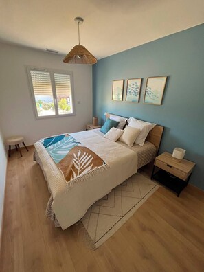 A bedroom with a bed, bedside tables, a window with blinds, and wall art. - A new, bright, air-conditioned house with a large terrace at the foot of the Luberon (Lauris)