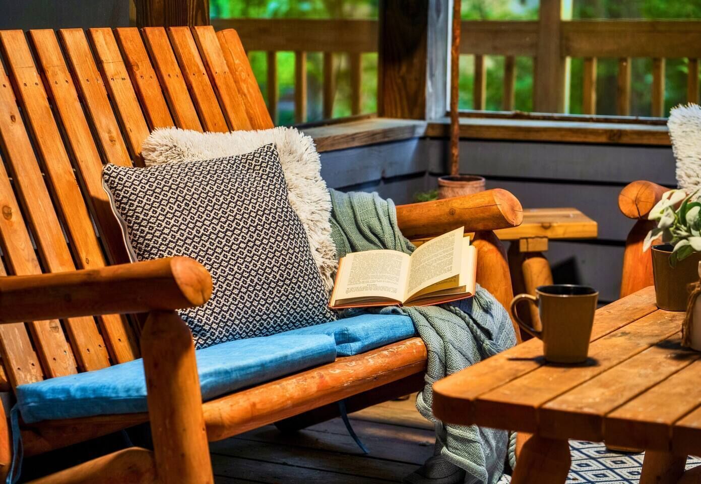 Une terrasse en bois avec une chaise en bois, une table et un livre.