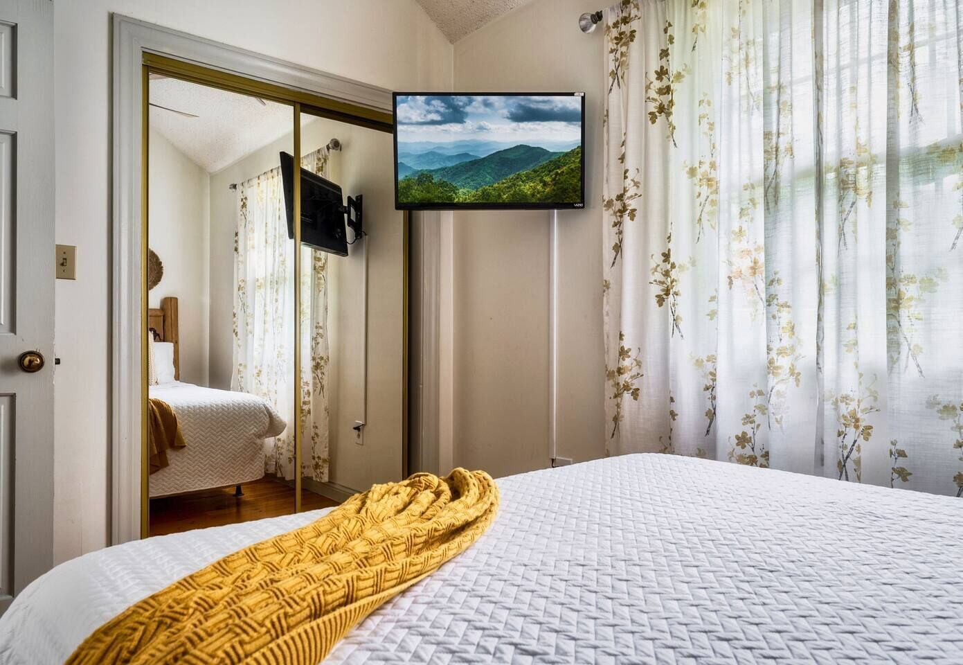 Une chambre d’hôtel avec un lit, un téléviseur fixé au mur et une vue sur un paysage montagneux.