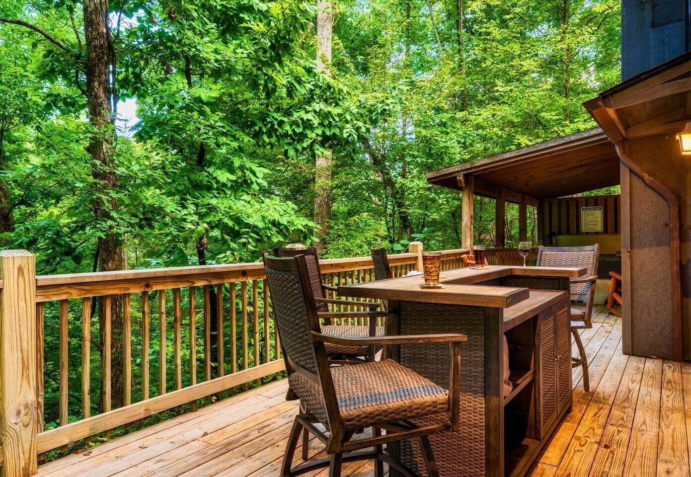 Une terrasse en bois, agréée de mobilier d’extérieur, entourée d’une forêt dense.