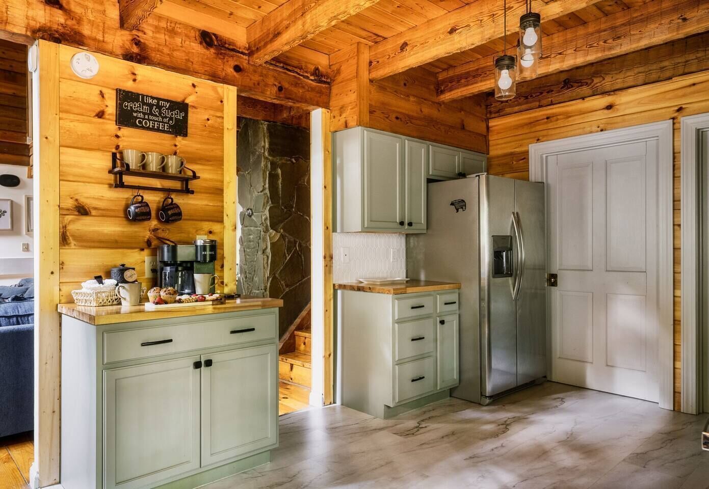 Une cuisine avec des murs en bois, un mur d’accent en pierre et un réfrigérateur en acier inoxydable.