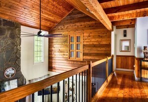 A wooden interior with a stone wall, a wooden staircase, and a ceiling fan. - Rustic Cabin with Fire Pit and Hot Tub (Pigeon Forge)
