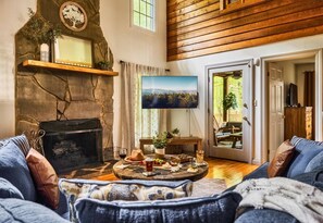 A cozy living room with a fireplace, a television, and a dining area with a table set for a meal. - Rustic Cabin with Fire Pit and Hot Tub (Pigeon Forge)