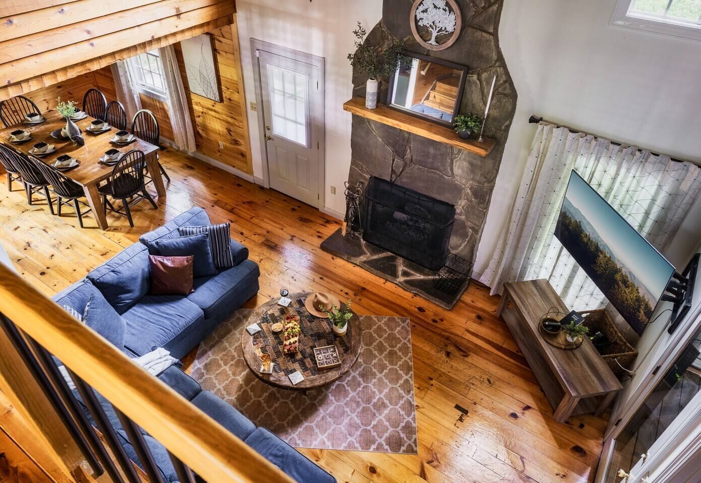 Een gezellig interieur van een blokhut met een eethoek, een open haard, een bank en een televisie.