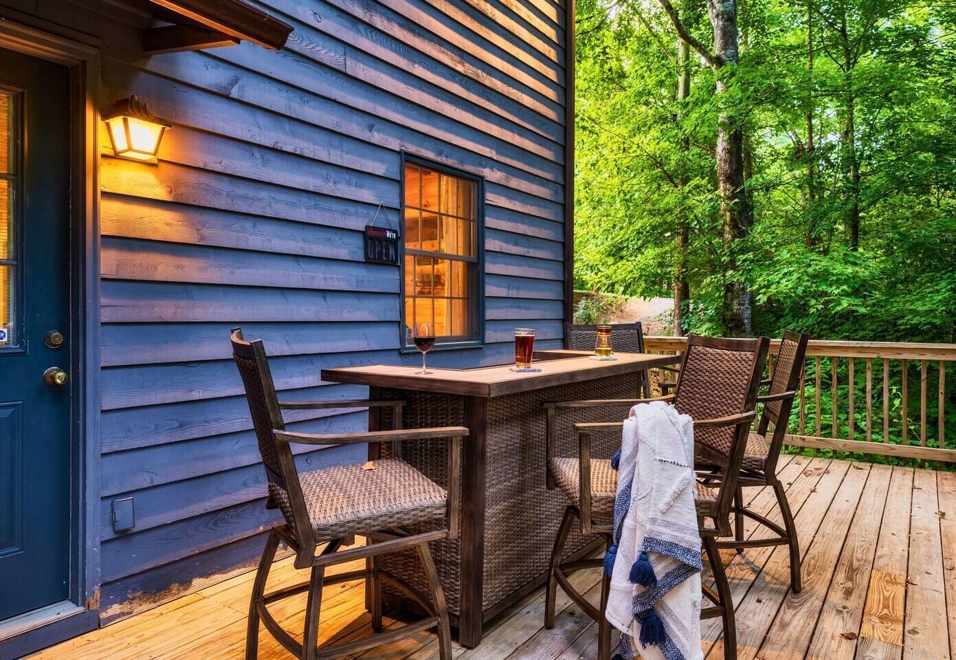 Een houten terras met een tafel, stoelen, een deur en een raam met een bord.