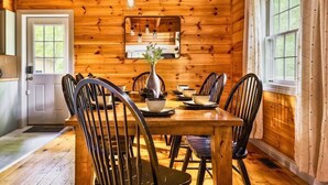 Un interior de madera con una mesa de comedor, sillas y lámparas colgantes.