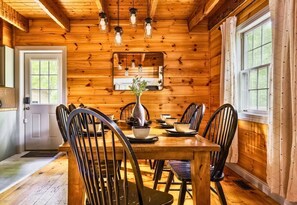 Ein Holzinterieur mit Esstisch, Stühlen und hängenden Leuchten.