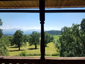 Eine Holzkonstruktion mit Blick auf eine grüne Landschaft und ferne Berge.