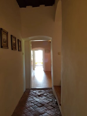 A hallway with a tiled floor leading to a bright room.