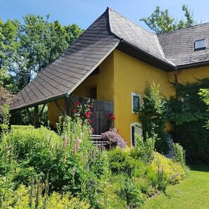 Ein gelbes Haus mit geneigtem Dach und einem kleinen Fenster.