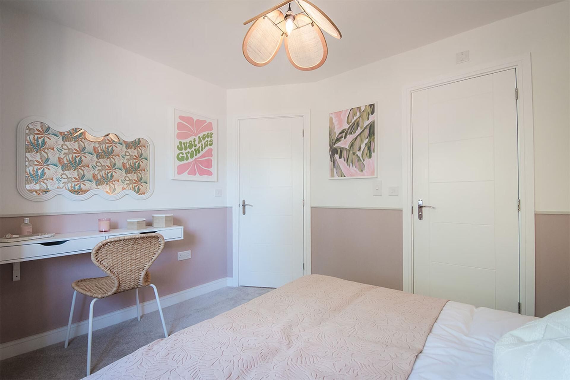 A bedroom with a bed, a desk, a chair, and artwork on the walls.