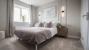 A bedroom with a bed, bedside table, lamp, and a window with curtains.