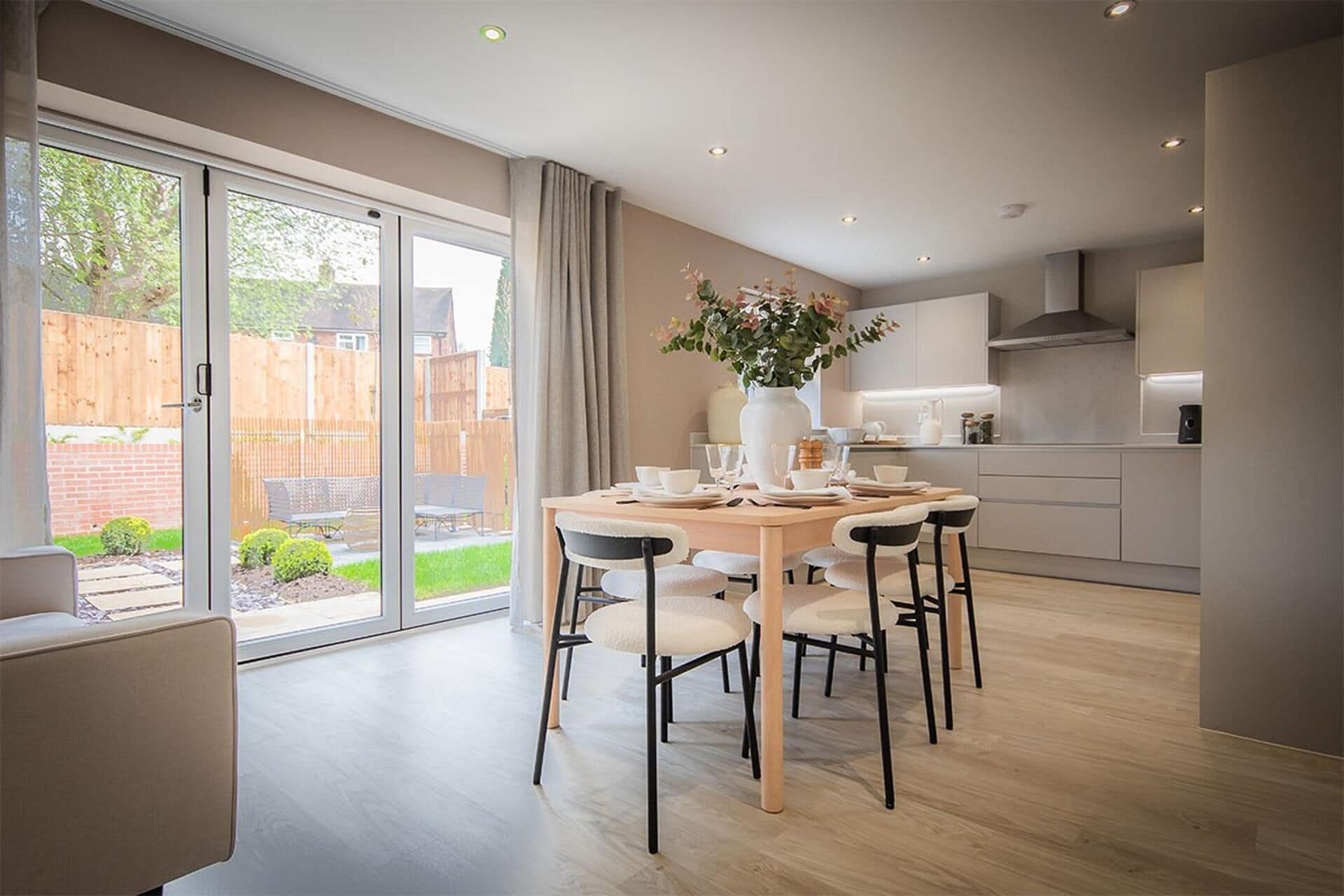 Una cocina moderna con comedor, ventanas amplias y vista al jardín trasero.