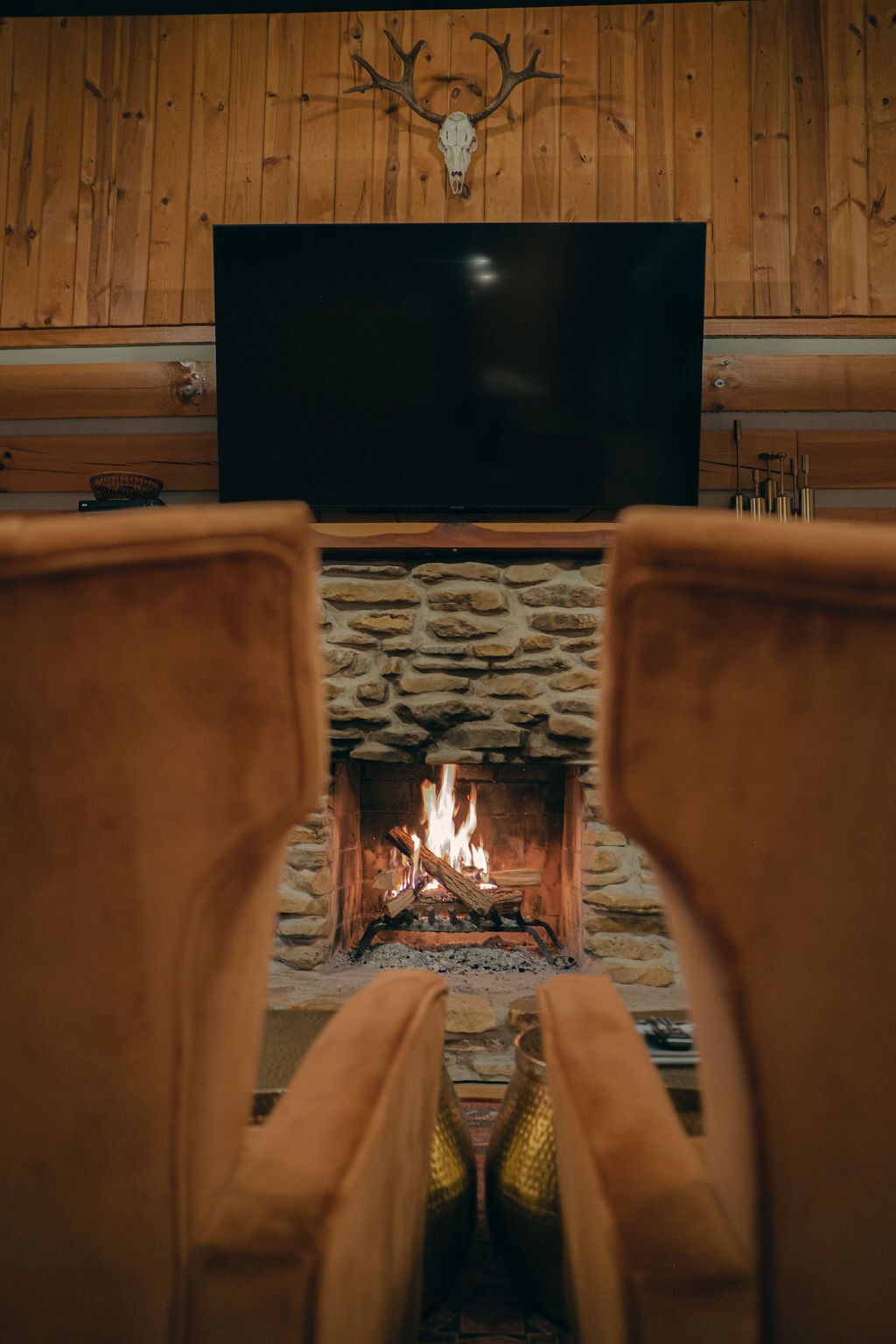 Een open haard met een stenen omlijsting en een televisie die erboven aan een houten wand is bevestigd.