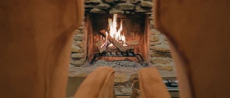 A fireplace with a stone surround and a television mounted above it on a wooden wall.