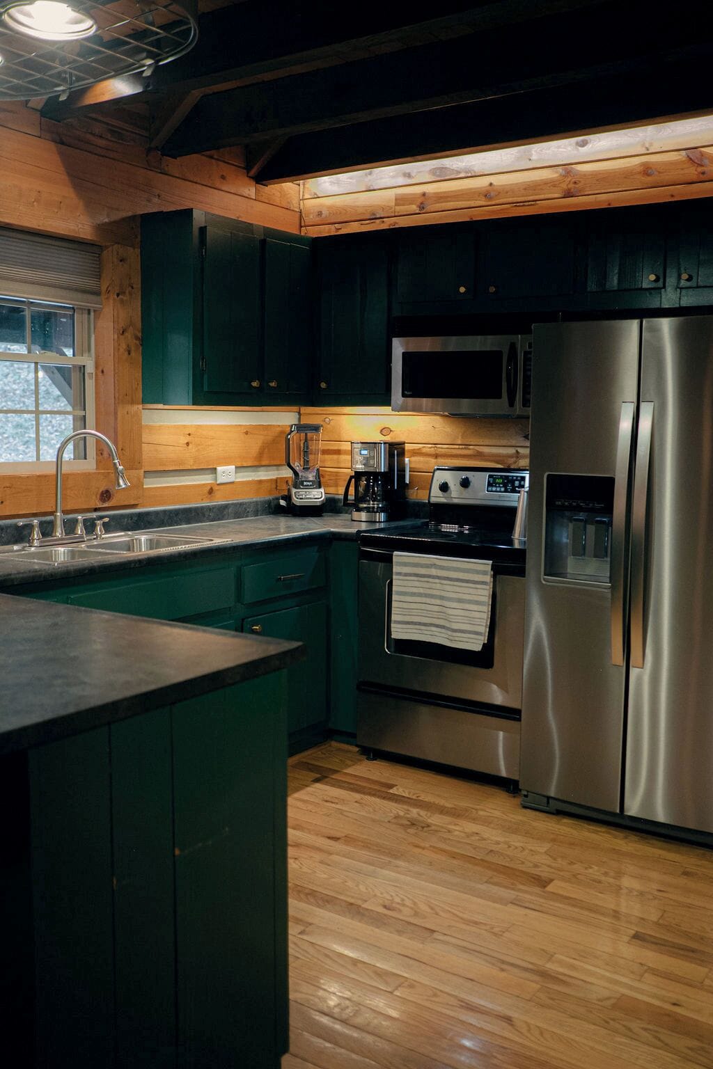 A kitchen with wooden cabinets, a stainless steel refrigerator, a stove, and a sink.