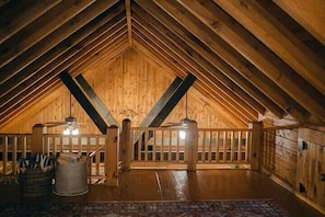 A wooden attic room with a sloped ceiling, a wooden railing, and a rug on the floor. - The Willow Nest Cabin, Stone fireplace, Cornhole, Kayaks, Views, Porch (Stanton)