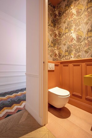 A bathroom with a toilet, wooden paneling, and a patterned wallpaper. - Exceptional Family Apartment 8P A/c- Victor Hugo (Paris)