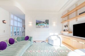 A modern living room with a large flat-screen TV, a sofa with purple cushions, a bean bag, and a painting of a pool on the wall. - Exceptional Family Apartment 8P A/c- Victor Hugo (Paris)